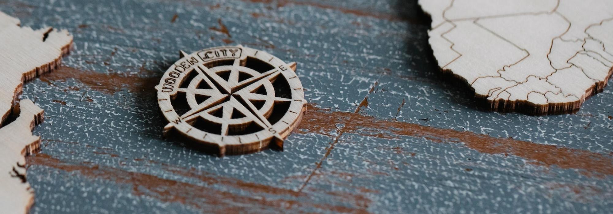 A compass rose sits on a blue and white wooden world map