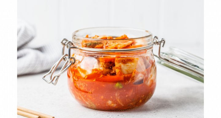 Glass jar containing kimchi sits on a white counter